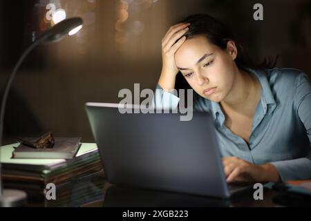 Overwhelmed worker working online with a laptop in the night Stock Photo