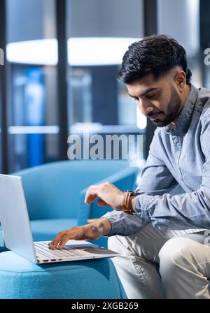 Using laptop, man checking time on smartwatch while working in modern office, copy space Stock Photo