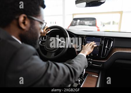 Businessman exploring car features at dealership in showroom Stock Photo