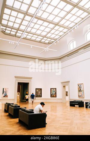 Man Reading Phone on a Couch in an Art Gallery With a Glass Ceiling Stock Photo