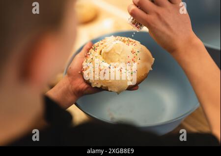 Overhead view of child shaking sprinkles on Easter egg basket cookies Stock Photo