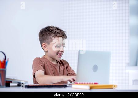 Distance learning online education. A schoolboy is studying at home using a laptop. Home distance learning. Stock Photo
