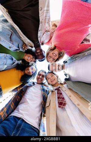 Happy young group of people smiling at camera standing in circle outside Stock Photo