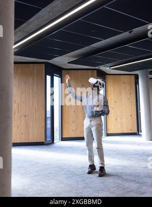 Using VR headset, man exploring virtual environment in modern office space Stock Photo