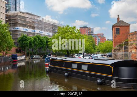 Black barge, lift bridge and trees at Castlefield Bridgewater Canal Basin, Manchester, UK, on a sunny June day with blue sky. Stock Photo