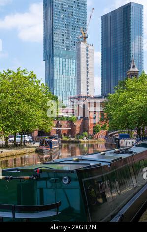 Black barge, lift bridge and trees at Castlefield Bridgewater Canal Basin, Manchester, UK, on a sunny June day with blue sky. Stock Photo