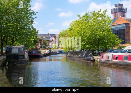 Black barge, lift bridge and trees at Castlefield Bridgewater Canal Basin, Manchester, UK, on a sunny June day with blue sky. Stock Photo