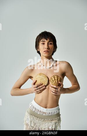 A beautiful woman in stylish attire gently cradling a shell on her chest. Stock Photo