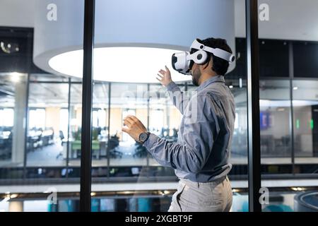 Using VR headset, man interacting with virtual environment in modern office, copy space Stock Photo