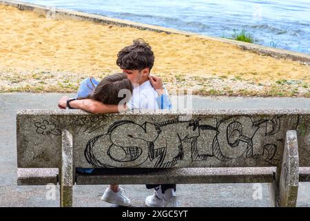 Two young lovers embracing on a riverside seat - Tours, Indre-et-Loire (37), France. Stock Photo