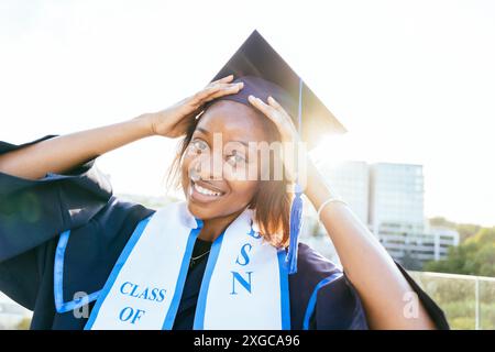 Portrait of cheerful Black woman in a graduation gown Stock Photo