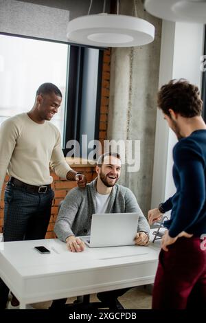 Teamwork in spacious eco office in loft style. Two caucasian men and african american coworker debating and one of them working on laptop. Stock Photo