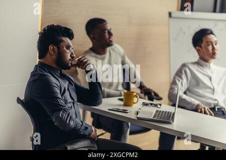Group of strategy managers reading last business reports from exchanges on laptop and pesonal computers during business meeting coloborating together Stock Photo