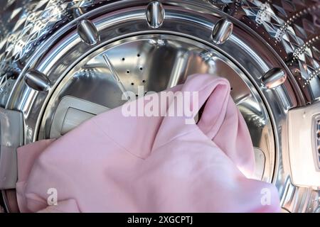 Close up view on clothes dryer with washed and dried shirts in and door open. Metal drum of the washing machine for washing clothes in the household. Stock Photo