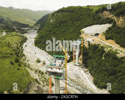 Kazbegi, Georgia - 7th july, 2024: aerial view cranes and bridge foundation pillars on construction site of new highway road project built by chinese Stock Photo