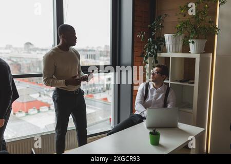 Successful entrepreneurs working over startup project on meeting in modern bright office interior brainstorming, working on laptop and flipchart. Stock Photo