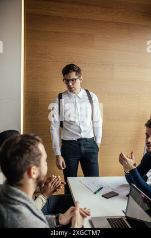 Young sales manager in white shirt standing with his report on business meeting. Male chief executive putting his ideas during presentation in boardro Stock Photo