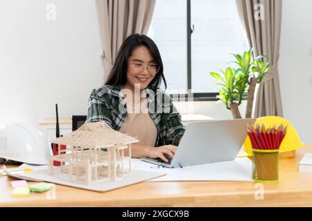 Mature female designer looks at laptop in her office, confident in her expertise and style of creativity. Senior design professional using a laptop an Stock Photo
