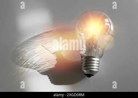 Small fluorescent light bulb. Innovation. Inspiration. Modern fluorescent light bulb on a gray background creates a reflection. Stock Photo