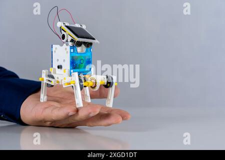 A plastic robot is in the hand of a student placed on the table, experimenting with learning with his hands, improving his skills. School writes code Stock Photo
