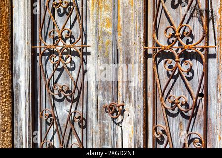 Iron bars on the door are rusted and have a vintage look. Wooden door has a lot of detail, including grates. Scene is nostalgic and somewhat eerie Stock Photo