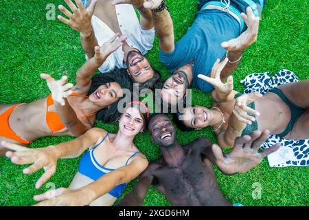 Group of friends lying on grass - enjoying a sunny day - outdoor fun and relaxation, diverse group of friends - happy and carefree moments, vibrant su Stock Photo