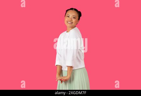 Young Asian Woman Smiling Against Pink Background Stock Photo