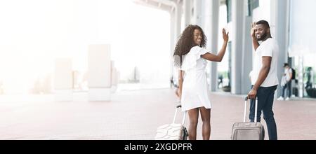 Smiling Couple Waving Goodbye at Airport Terminal Stock Photo