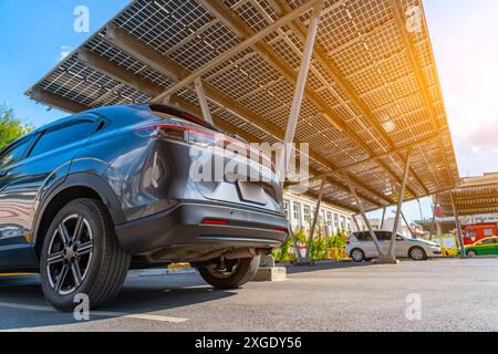 Solar panels installed over parking lot with parked cars for effective generation of clean energy. Stock Photo