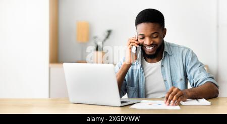 Cheerful african businessman checking financial reports and talking on phone Stock Photo
