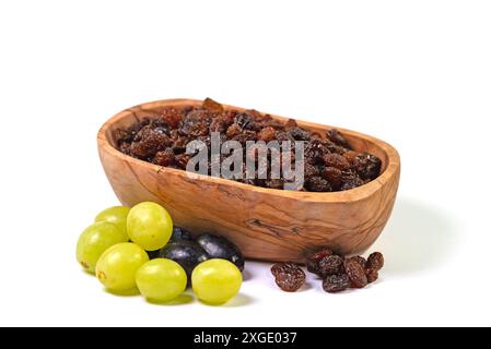 Dried grapes in a wooden bowl against a white background Stock Photo
