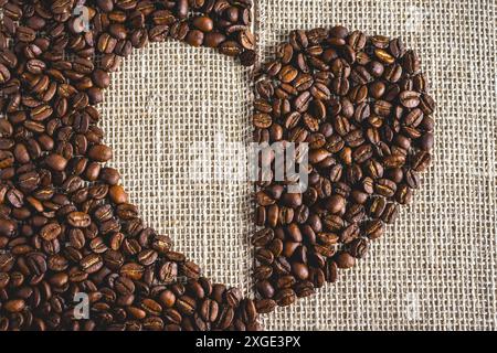 Coffee beans laying down in a heart shape, On a Burlap fabric. Background voor coffee related products. Stock Photo