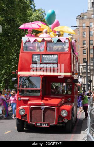 London Pride Parade 2024 destination on the front of a private hire bus by Traditional Travel Ltd, with people celebrating on the top open deck. UK Stock Photo