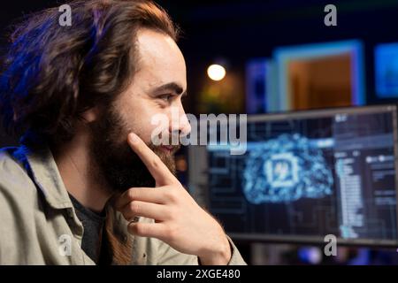 Smiling computer engineer updating artificial intelligence neural networks, satisfied after finishing writing binary code script. Cheerful system administrator happy after upgrading high tech AI Stock Photo