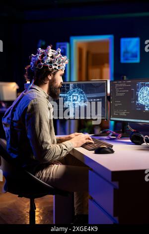 Software developer with EEG headset on writing code allowing him to transfer mind into computer virtual world, becoming one with AI. Transhumanist using neuroscientific tech to gain superintelligence Stock Photo