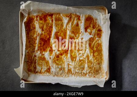 oven tray with baking paper and juice of meat after roasting on grey kitchen table, top view. process of making crispy chicken wings Stock Photo