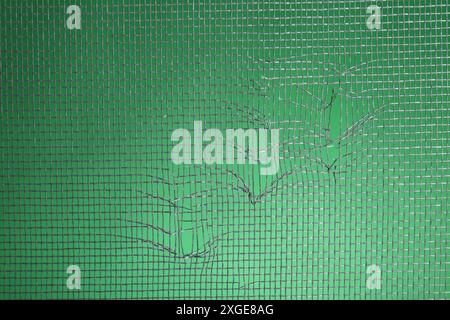 Torn window screen against green background, closeup Stock Photo