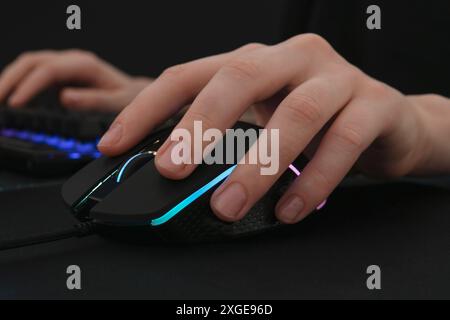 Gamer using modern wired computer mouse at dark table, closeup Stock Photo