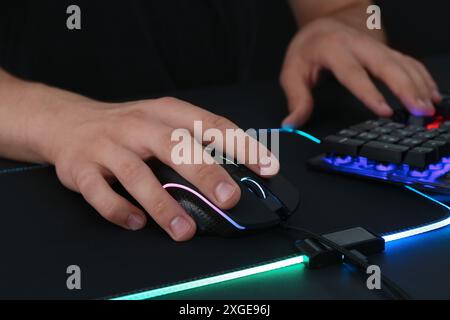Gamer using modern wired computer mouse at black table, closeup Stock Photo
