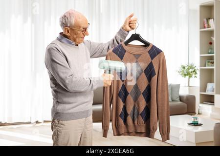 Elderly man using a hand steam iron at home Stock Photo