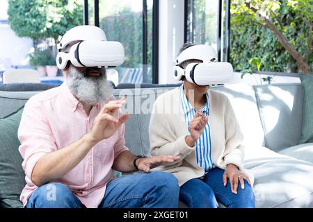 Senior couple using VR headsets, experiencing virtual reality at home Stock Photo