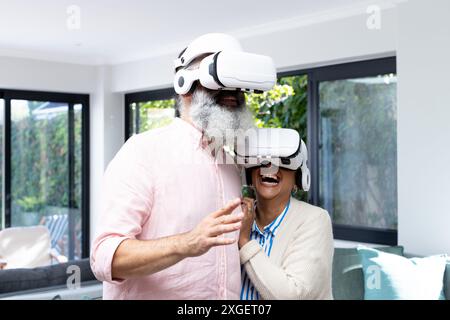 Wearing VR headsets, senior couple laughing and enjoying virtual reality experience Stock Photo