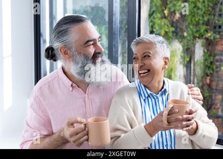 Smiling senior couple enjoying coffee together, sharing joyful moment indoors Stock Photo