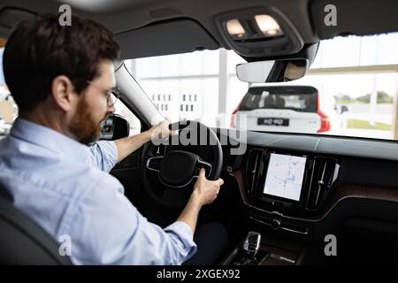 Businessman inside car dealership showroom test driving vehicle Stock Photo