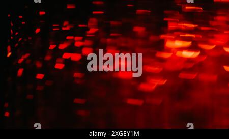 Bokeh light. Color flare. Blur confetti. Festive decor. Defocused red orange led bulbs sparkle glare flicker soft focus glitter tinsel effect on black abstract background. Stock Photo
