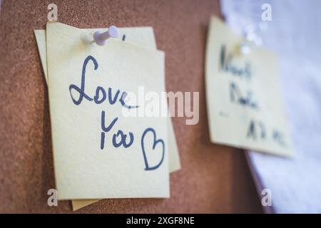 Close up of pinned note ?Love you? on cork board Stock Photo