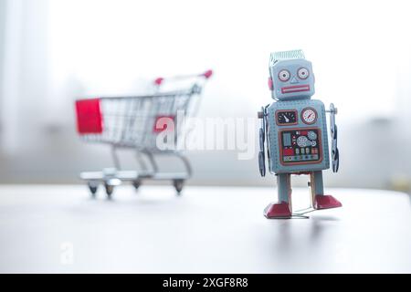 Online-Shopping concept: Toy robot and Miniature shopping cart Stock Photo