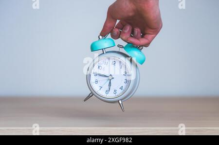 Male hand is holding a retro styled white alarm clock, isolated Stock Photo