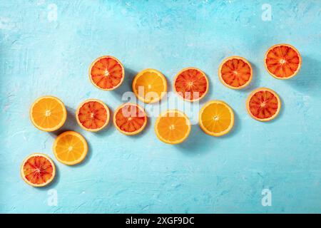 Blood oranges and regular oranges, overhead flat lay shot on a blue background with copy space. Summer banner Stock Photo