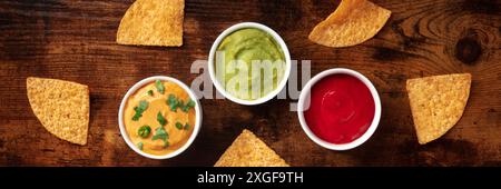 Nacho chips and dips panorama, top shot on a dark rustic wooden background Stock Photo